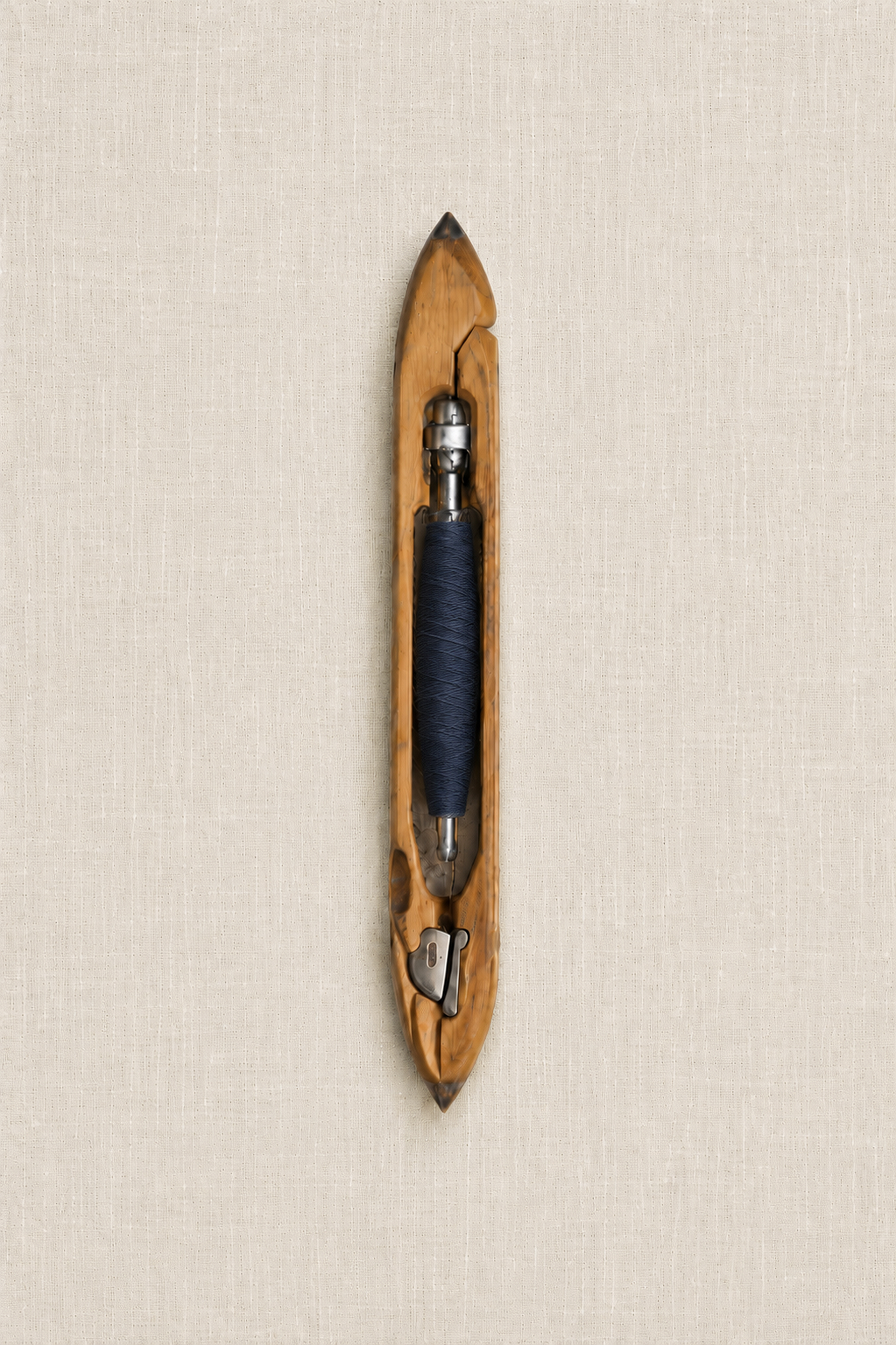 Traditional wooden weaving shuttle with navy thread